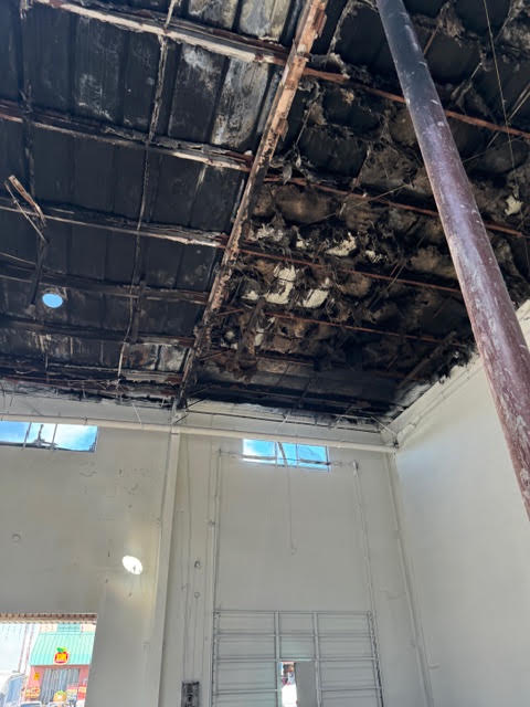 Fire-damaged ceiling and roof framing inside a commercial property