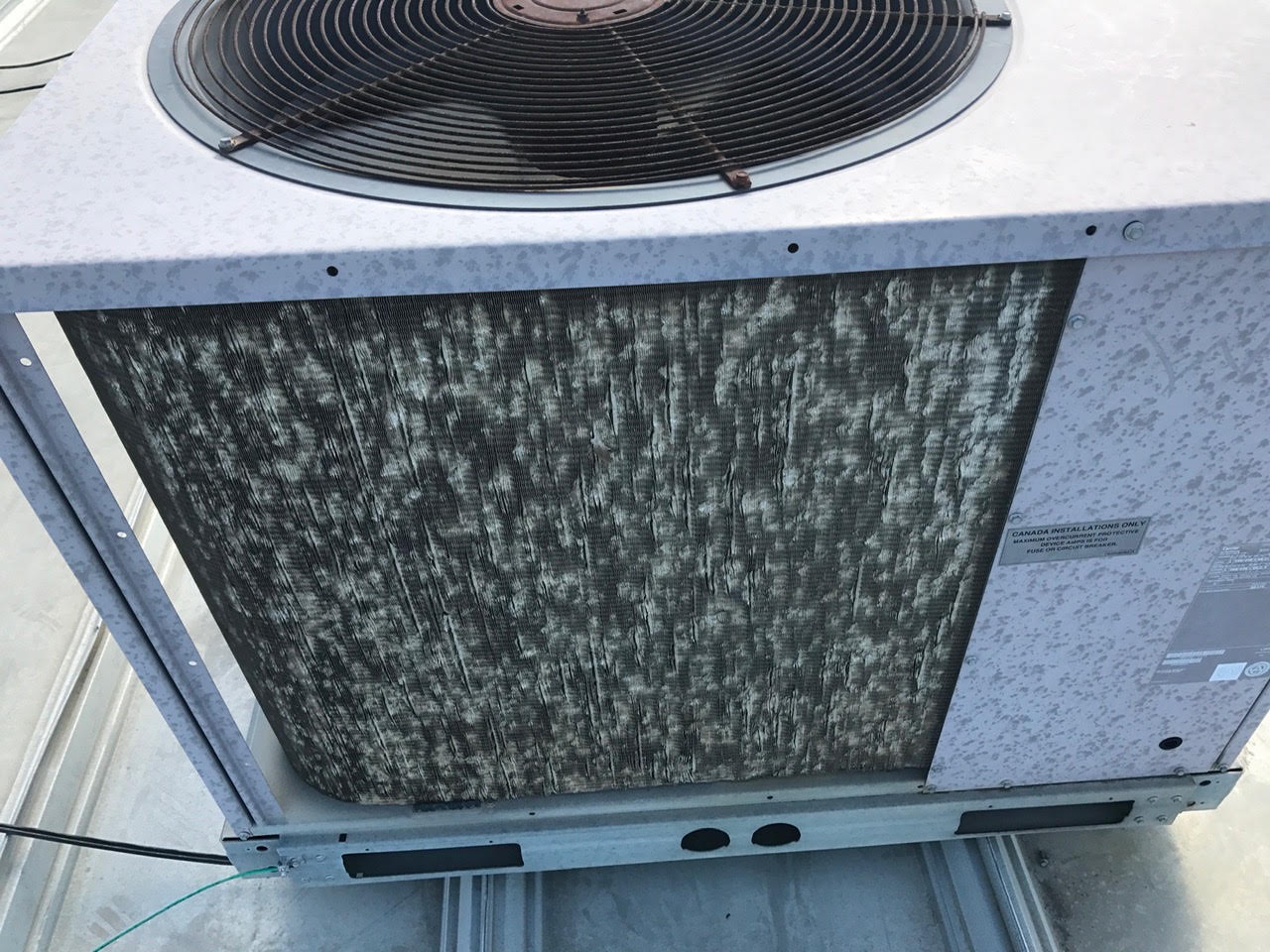 Commercial HVAC unit with marked exterior and damaged coil fins