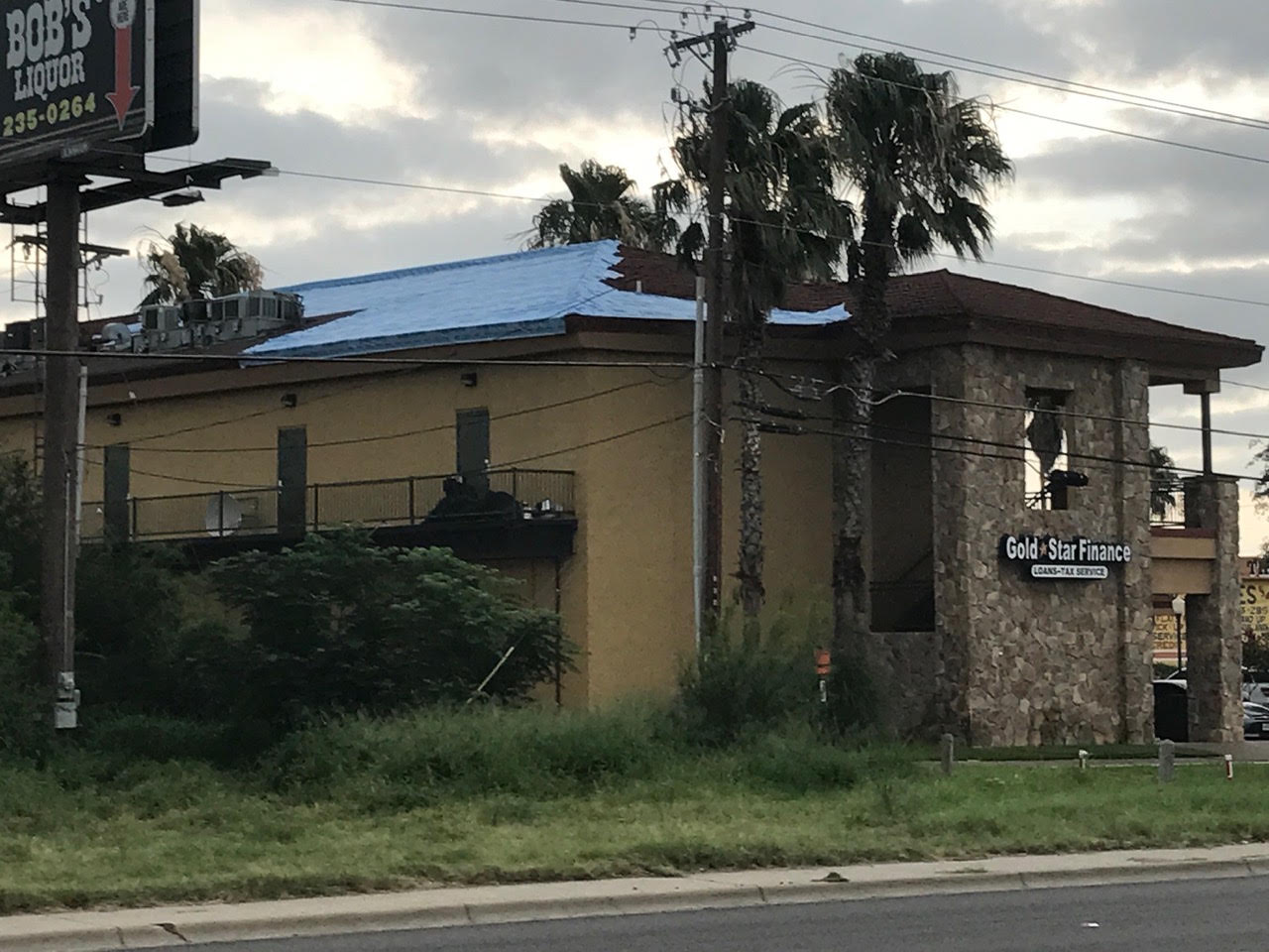 Commercial building with a roof partly covered by a blue tarp