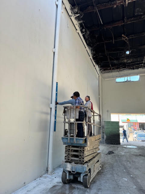 Inspectors using a level to examine a wall inside a fire-damaged building