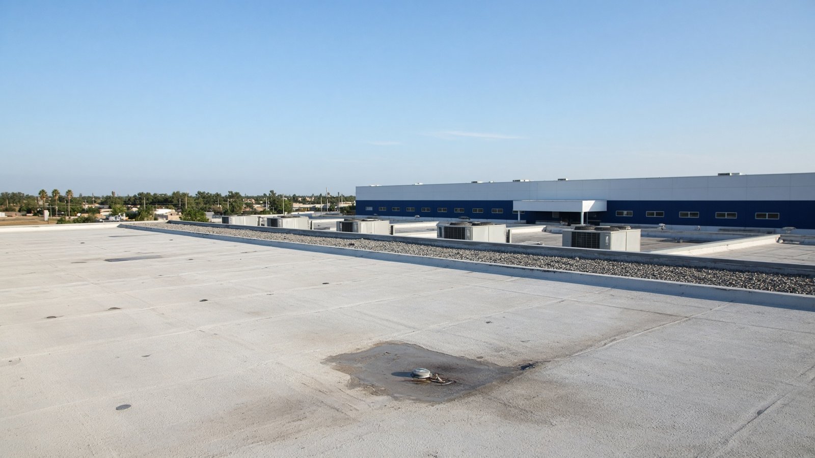 Low-slope commercial roof in South Texas daylight after hail wear