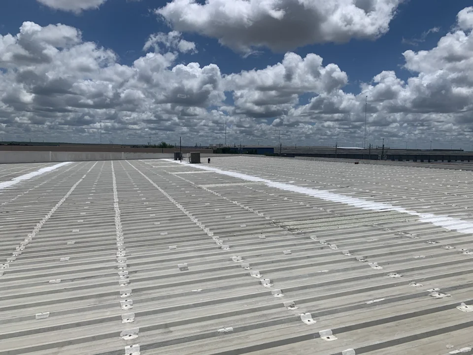 A wide inspection view records the metal panels, rows of fasteners, rooftop equipment and areas of white coating. It gives context for the close-up observations.