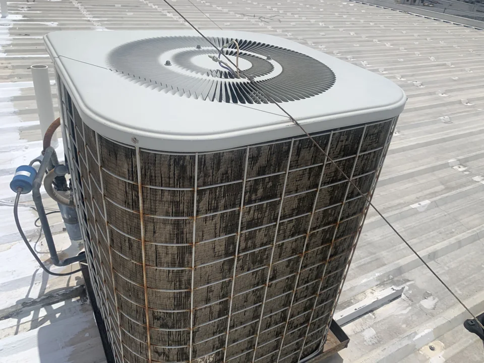 This rooftop air-conditioning unit has visibly distorted coil fins. We document equipment condition separately from the roof covering; the cause and repair needs require the full inspection record.