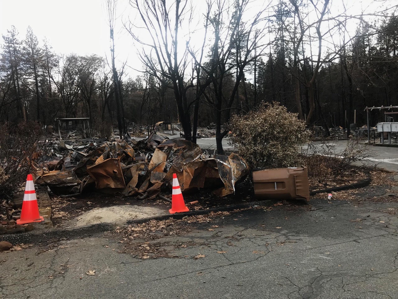 Fire-damaged residential property with debris and traffic cones
