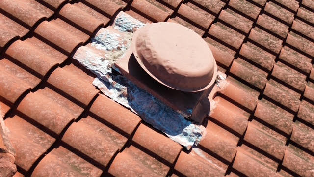 Residential tile roof vent inspected for hail damage