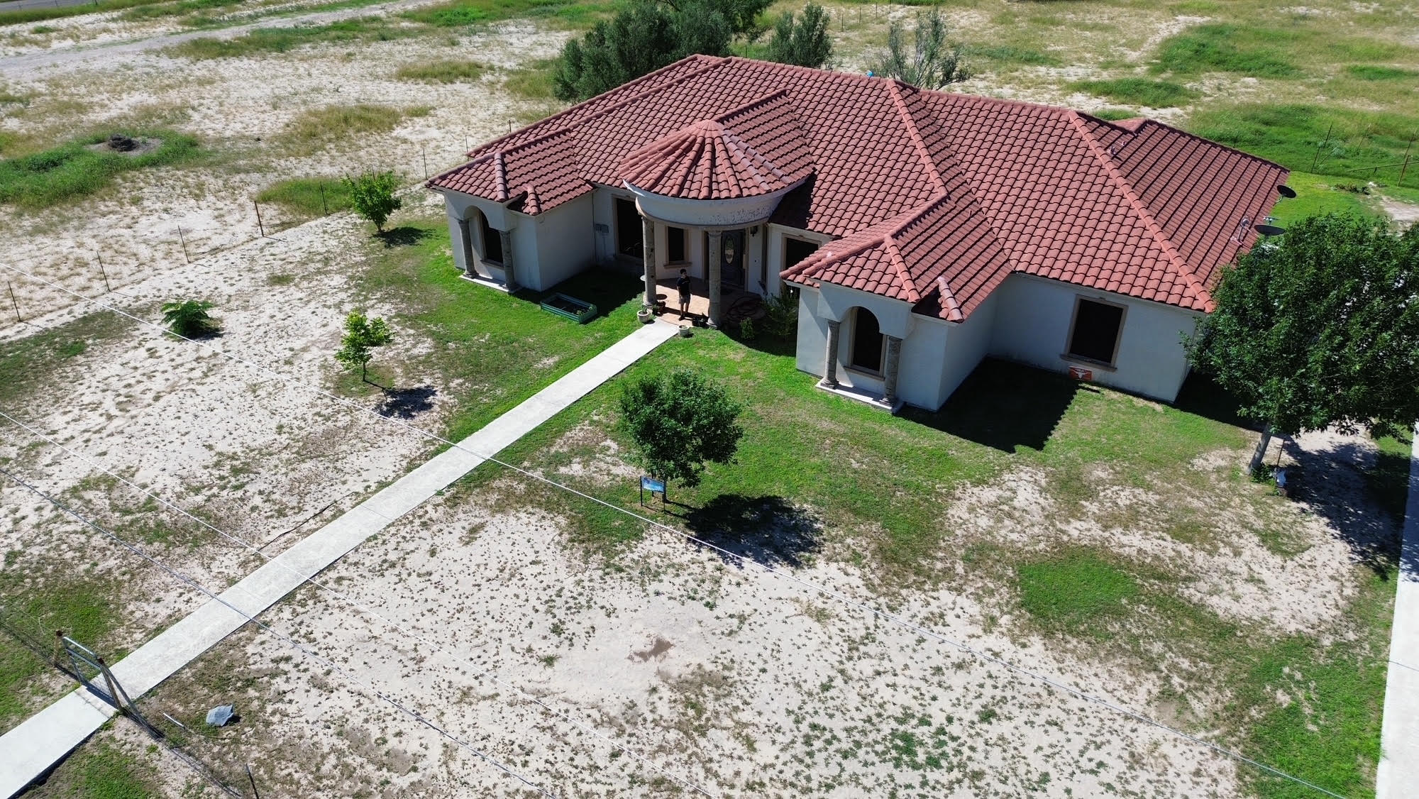 Aerial view of a tile-roof home and surrounding property